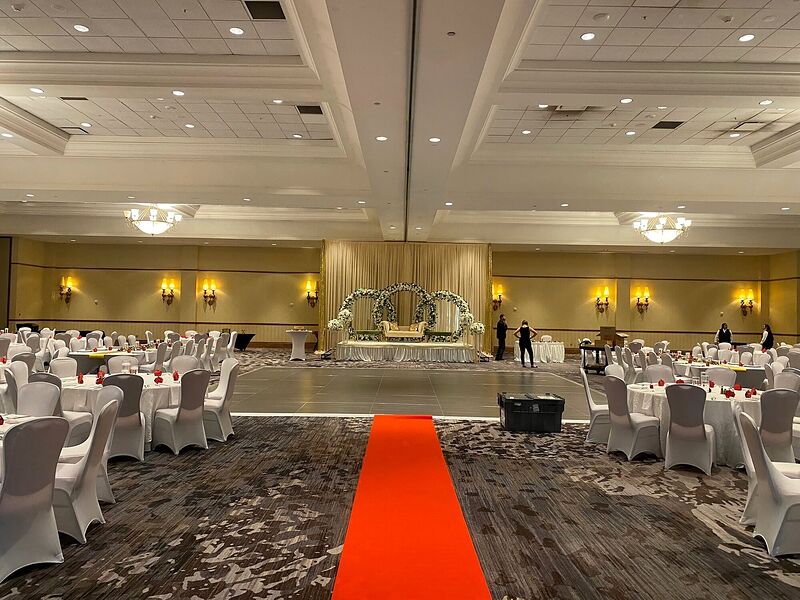 A hotel ballroom set for an event with a red aisle runner