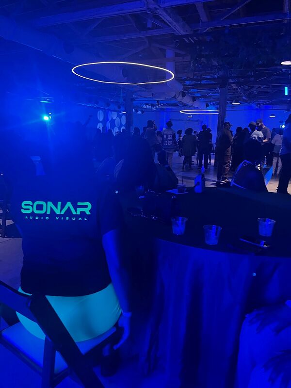 The Sonar Audio Visual branded booth facade lit in a blue hall