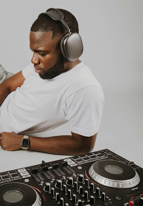 A DJ in headphones leaning over a controller