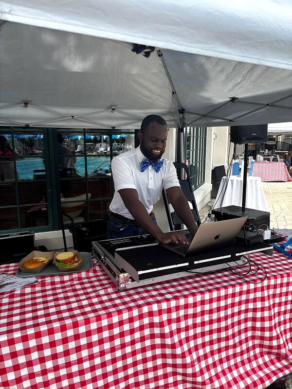 A DJ setup on a red checked tablecloth under a marquee