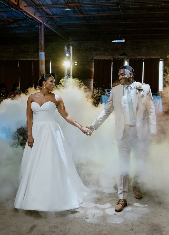 A newly married couple walking hand in hand through low fog