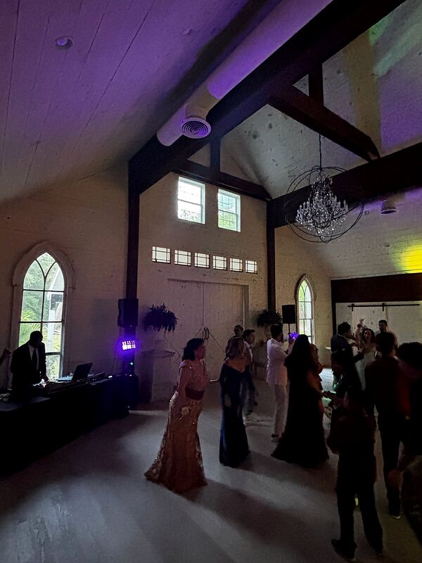 The same beamed venue lit in warm amber with guests dancing
