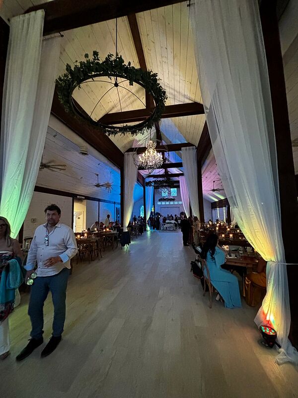 A venue in daylight with white draping and a hanging greenery wreath